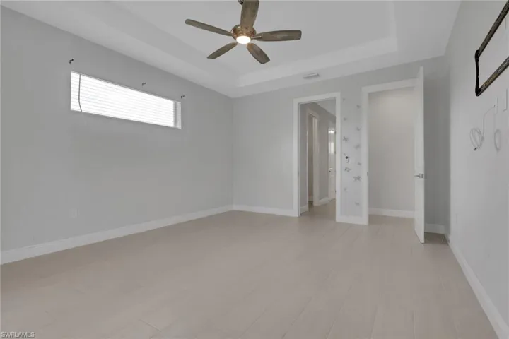 Owner's bedroom with tray ceiling, transom window for natural light, pool/lanai access through sliding glass doors.