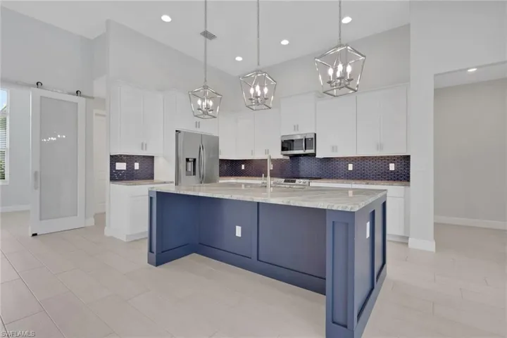 Island kitchen with granite counters, classic white shaker style cabinets with crown molding and crown molding.