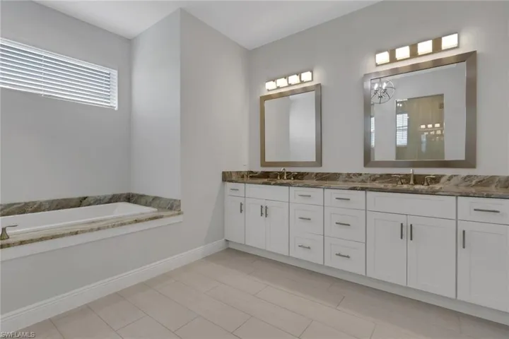 Owner's bath with dual vanities, matching granite counters, soaking tub and walk in shower
