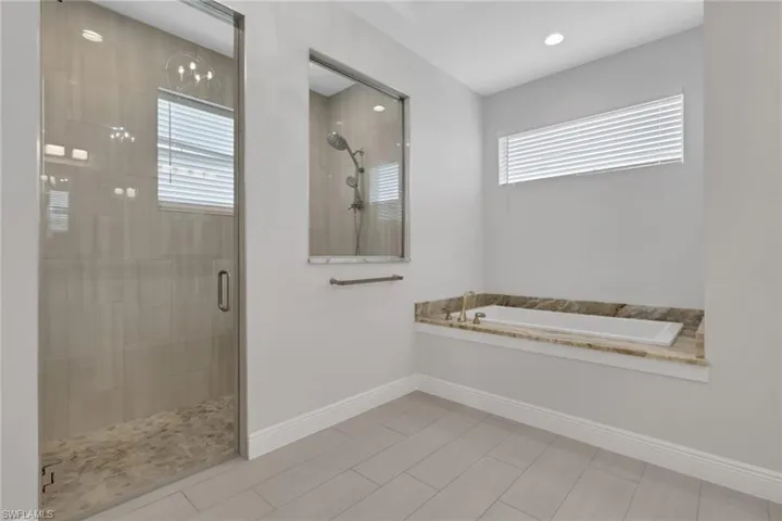 Owner's bath with dual vanities, matching granite counters, soaking tub and walk in shower