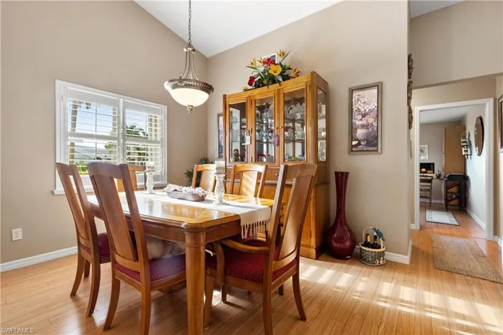Dining space with light hardwood / wood-style flooring and high vaulted ceiling