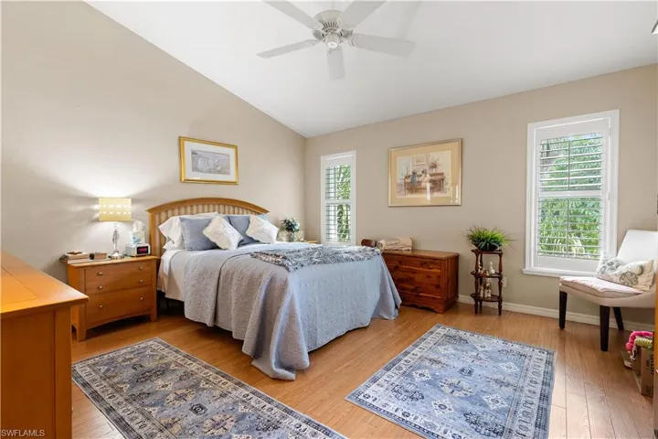 Bedroom with lofted ceiling, multiple windows, ceiling fan, and wood-type flooring