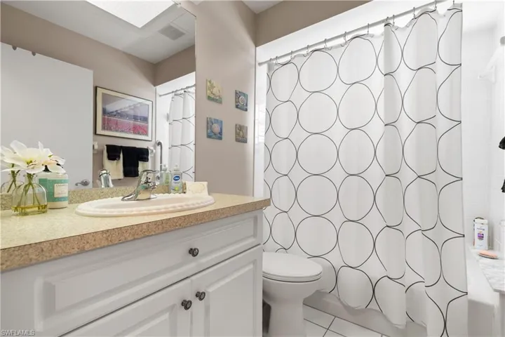 Bathroom with tile patterned floors, a shower with shower curtain, toilet, and vanity