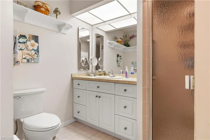 Bathroom with an enclosed shower, vanity, toilet, and tile patterned floors