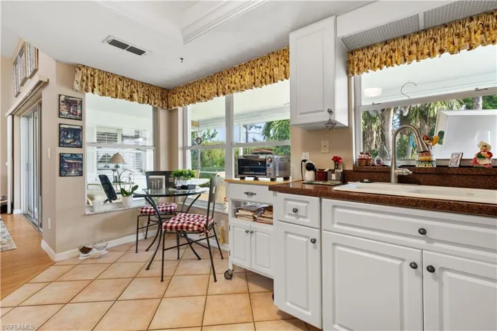 Kitchen with ornamental molding, light hardwood / wood-style flooring, sink, and white cabinets