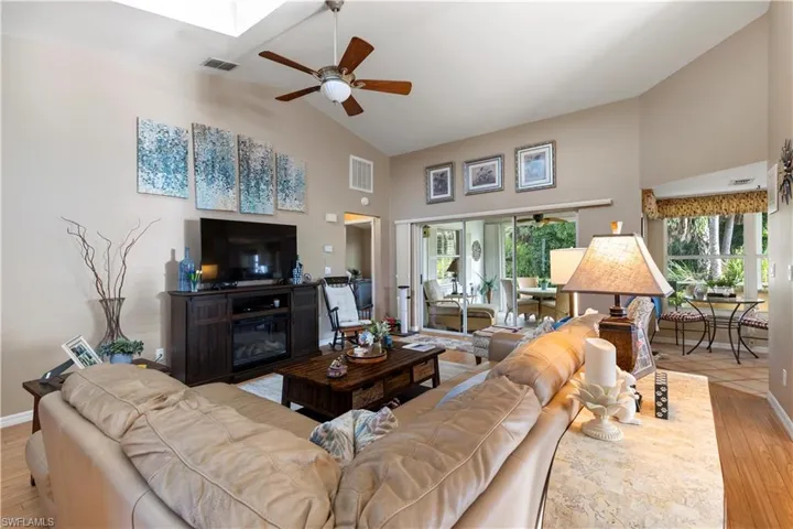 Living room with high vaulted ceiling, ceiling fan, and light hardwood / wood-style flooring