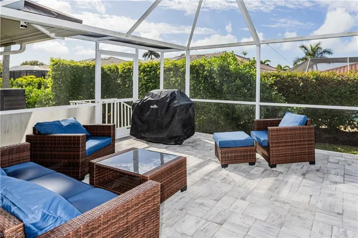 View of patio with grilling area, outdoor lounge area, and glass enclosure