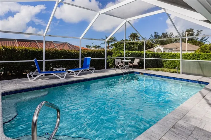 View of pool with a patio area and glass enclosure