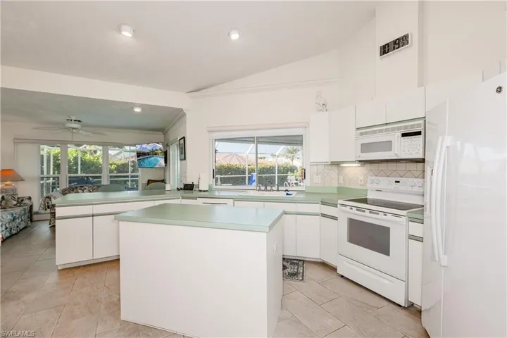 Kitchen with a kitchen island, white cabinets, white appliances, and kitchen peninsula