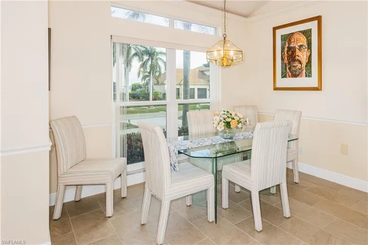 Tiled dining area featuring vaulted ceiling and a chandelier