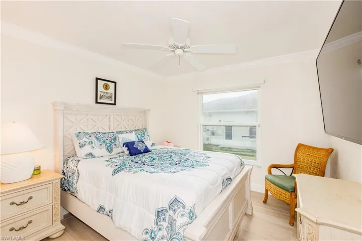 Bedroom with ornamental molding, ceiling fan, and light wood-type flooring