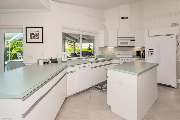 Kitchen with tasteful backsplash, white cabinetry, a kitchen island, and white appliances