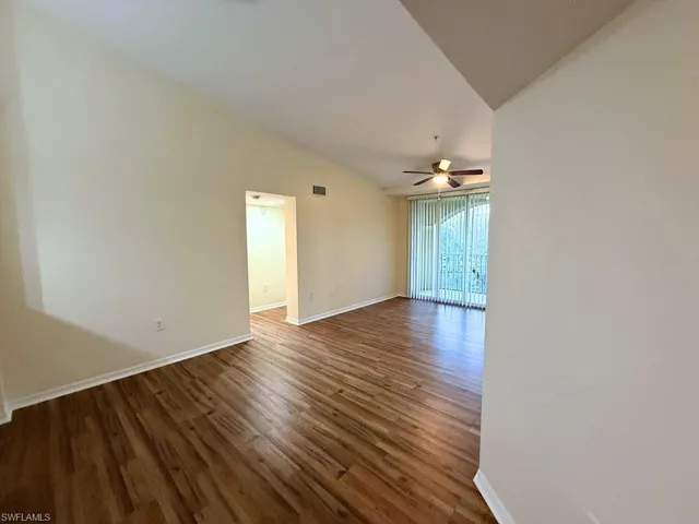 Spare room with dark wood-style flooring and lofted ceiling