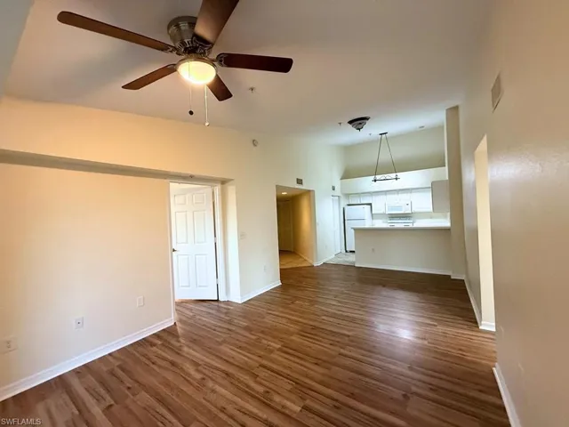 Unfurnished living room with dark wood finished floors and ceiling fan