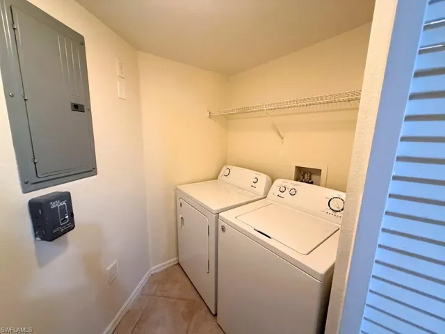 Laundry area with electric panel, washing machine and clothes dryer, and light tile patterned floors