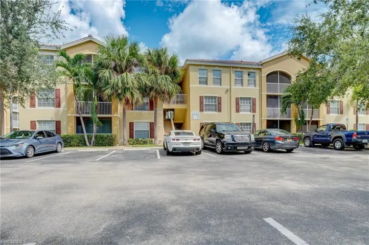 View of apartment building / complex featuring uncovered parking