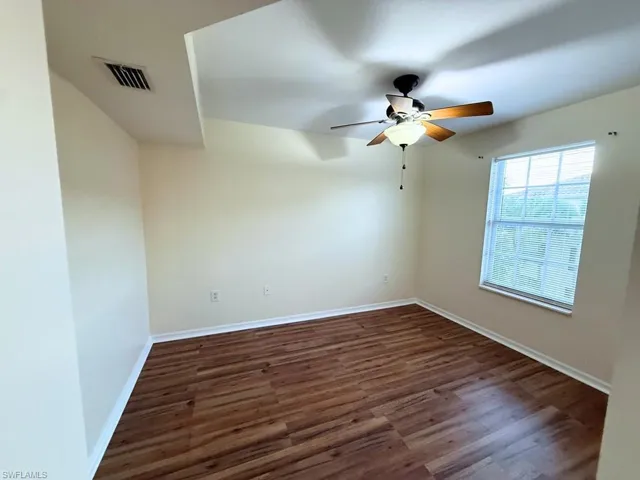 Empty room featuring dark wood-style floors and a ceiling fan