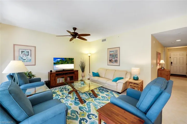 Living room with ceiling fan and light tile patterned flooring