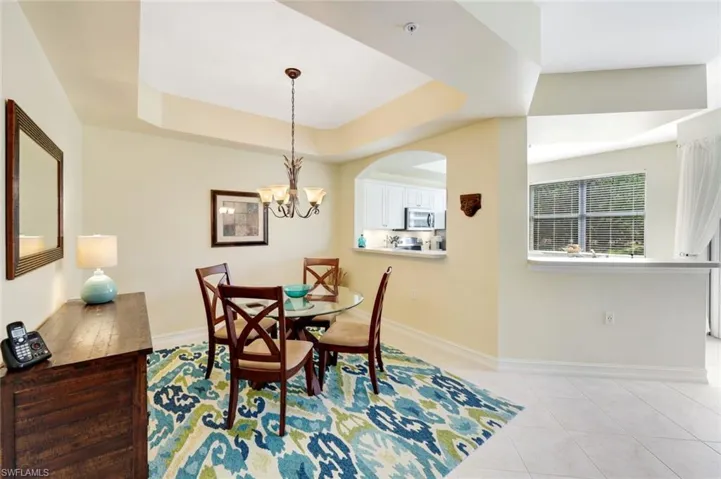 Dining space featuring a raised ceiling, light tile patterned floors, and a chandelier