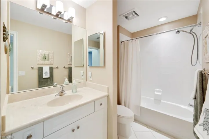 Bathroom with shower / tub combo, vanity, and light tile patterned floors