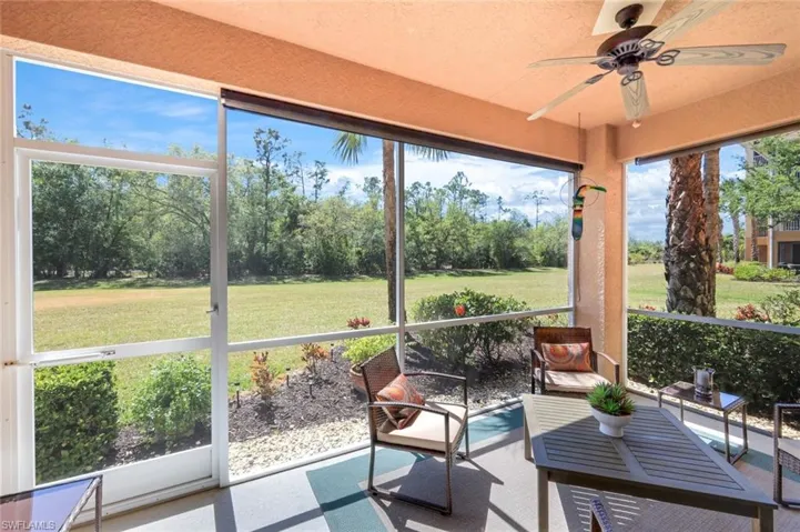 Sunroom featuring ceiling fan and view of scattered trees