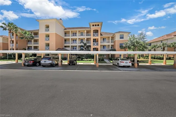 View of apartment building / complex featuring covered parking
