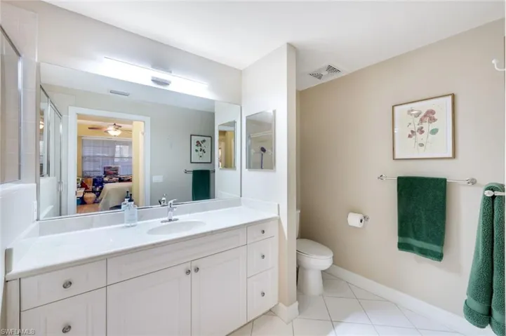 Ensuite bathroom featuring light tile patterned floors, vanity, ceiling fan, and a shower with shower door