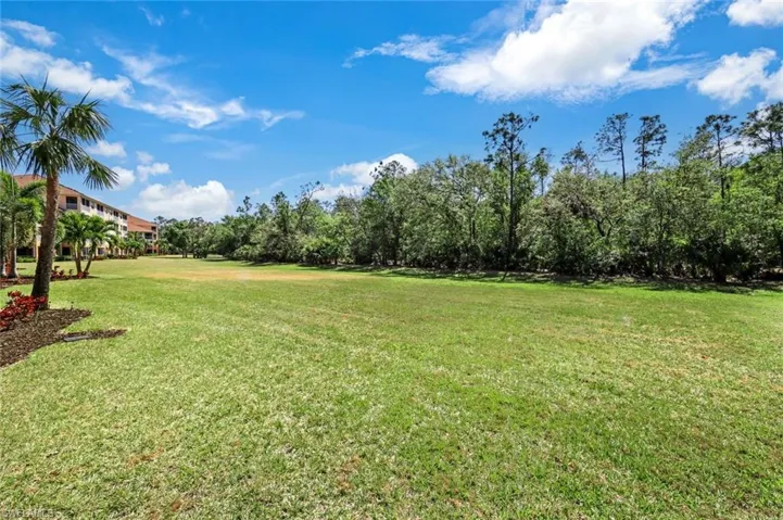 View of grassy yard featuring view of wooded area