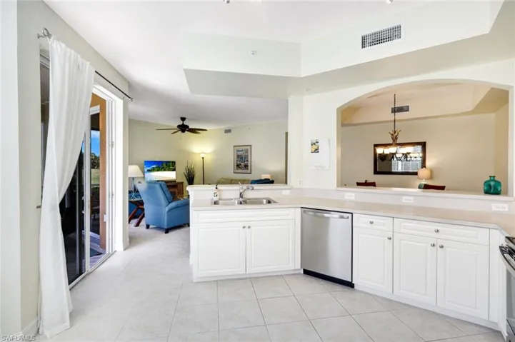 Kitchen featuring ceiling fan, stainless steel appliances, open floor plan, white cabinets, and light countertops