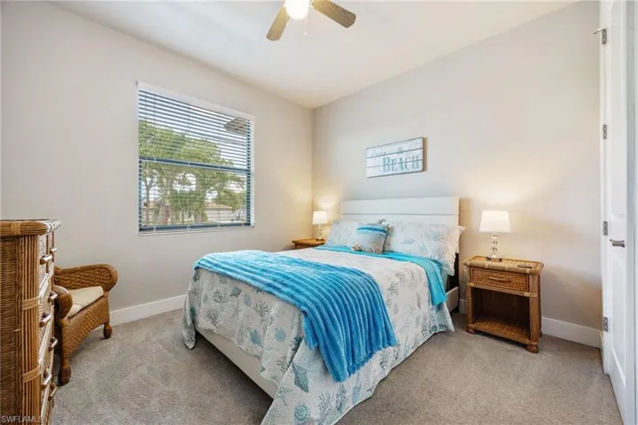 Bedroom featuring a ceiling fan, window with blinds, and light-toned carpet flooring
