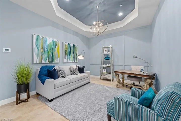 Living room featuring a tray ceiling, tile patterned floors, a chandelier, and ornamental molding