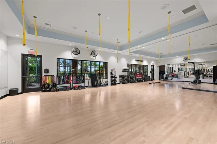 Workout area with a tray ceiling, light hardwood / wood-style flooring, and ornamental molding