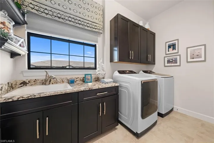 Laundry area with cabinets, independent washer and dryer, light tile patterned floors, and sink