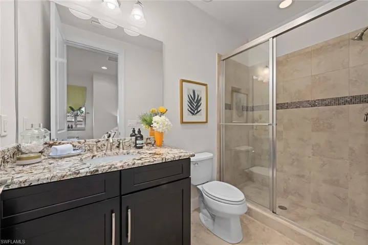 Bathroom featuring tile patterned flooring, vanity, toilet, and a shower with shower door