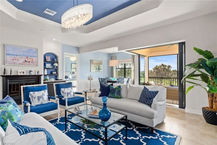 Tiled living room with built in shelves, an inviting chandelier, crown molding, and a tray ceiling