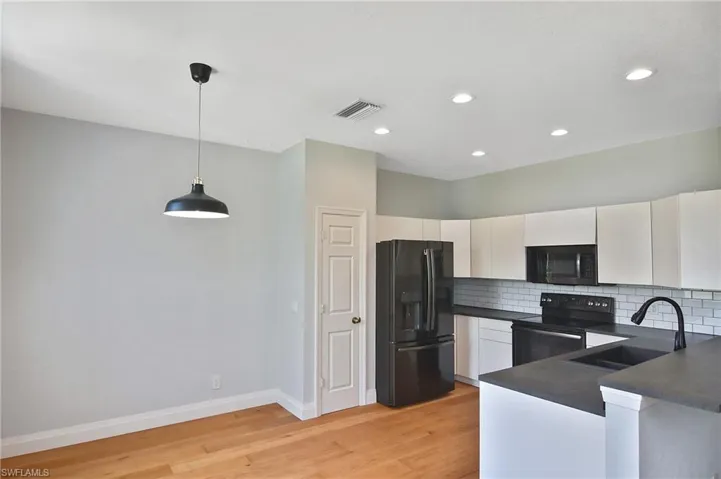 The open Kitchen features newer appliances, subway backsplash, and plenty of stone counter space.