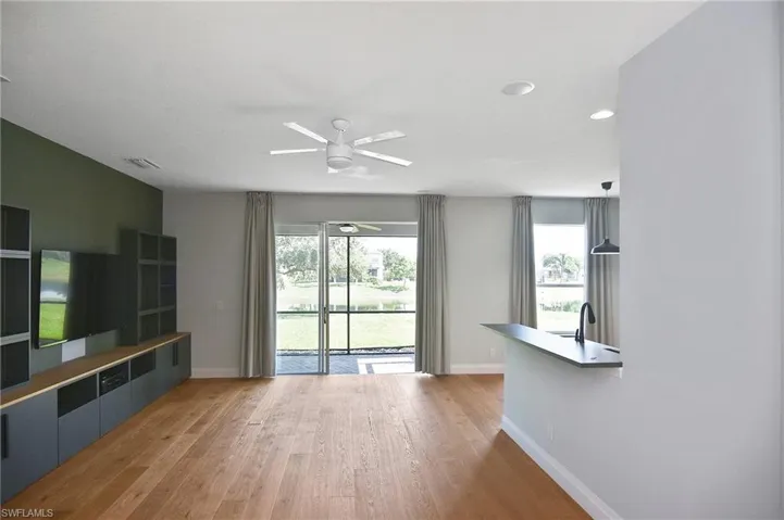 Great room features custom wall unit, wood flooring and glass sliders to the Lanai.