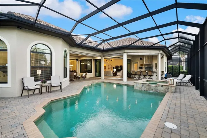 View of swimming pool featuring an in ground hot tub, screen enclosure, and a patio area