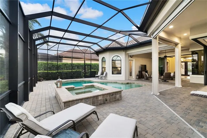 View of pool with an in ground hot tub, a patio, screen enclosure, and ceiling fan