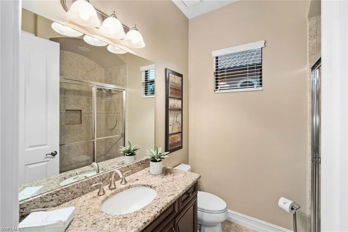 Bathroom featuring a shower with shower door, vanity, and toilet