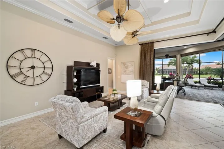 Living room with ceiling fan, ornamental molding, and light tile patterned floors
