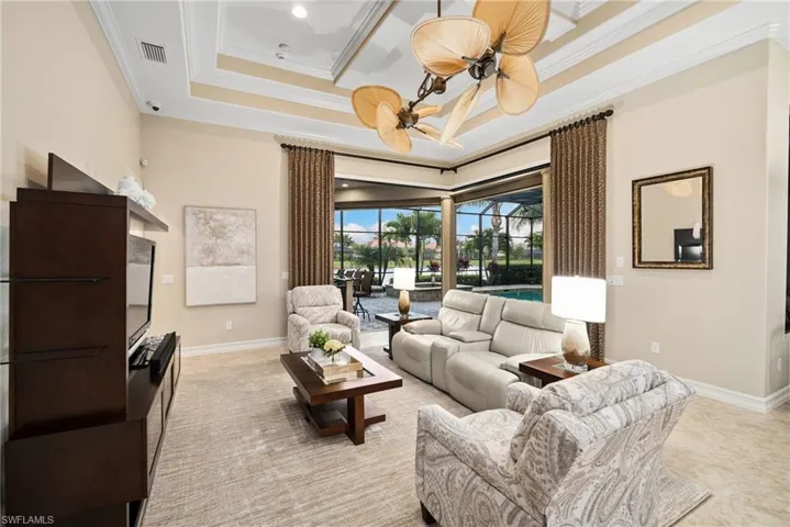 Living room with ceiling fan, crown molding, and a tray ceiling