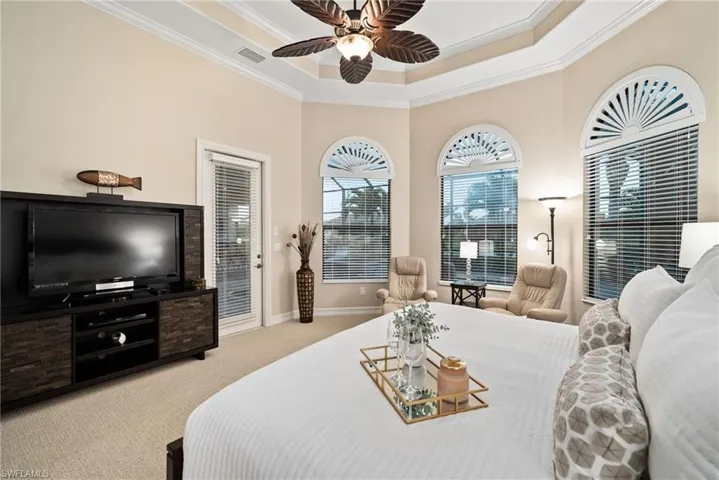 Bedroom featuring access to exterior, a tray ceiling, ceiling fan, light colored carpet, and ornamental molding