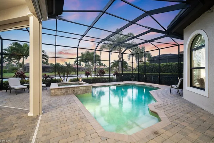 Pool at dusk featuring a patio, an in ground hot tub, and screen enclosure