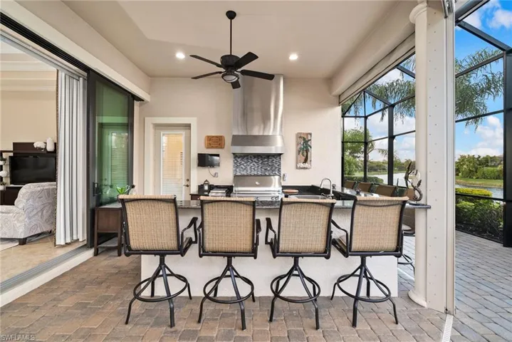 View of patio featuring a grill, screen enclosure, exterior kitchen, and ceiling fan