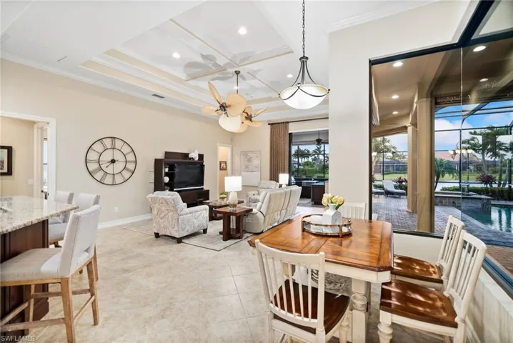Dining area featuring ornamental molding, light tile patterned floors, coffered ceiling, and ceiling fan
