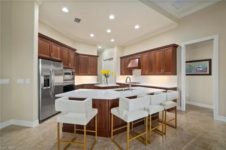 Kitchen with appliances with stainless steel finishes, sink, light tile patterned floors, a kitchen island, and a kitchen breakfast bar