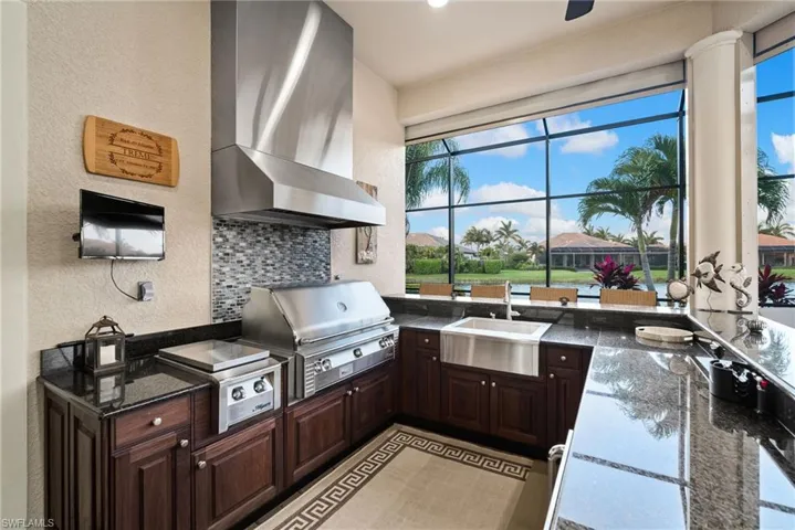 Kitchen featuring sink, decorative backsplash, wall chimney range hood, and dark brown cabinetry