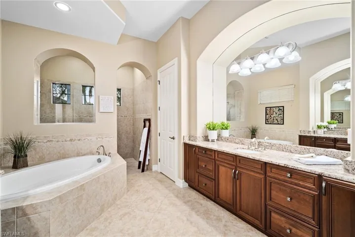 Bathroom with a relaxing tiled tub, vanity, and tile patterned floors