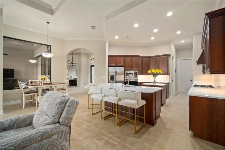 Kitchen with sink, appliances with stainless steel finishes, ornamental molding, and an island with sink